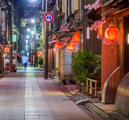 Empty street at night decorated with red lanterns and cherry blossom ornaments, evoking traditional Japanese ambiance.
