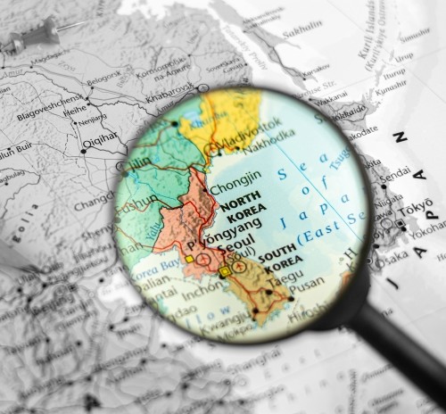 Map of North and South Korea viewed through a magnifying glass, highlighting their geographic locations in East Asia.