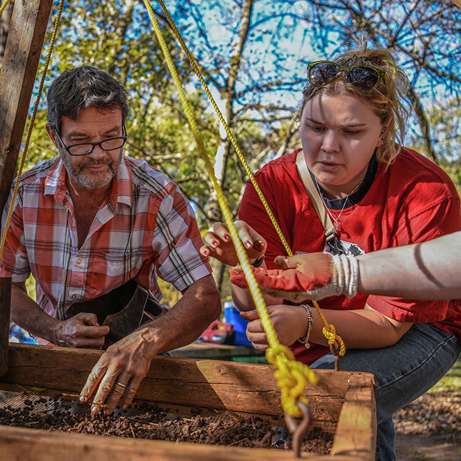 Kennesaw State professor and student looking curiously at artifact from dig site.