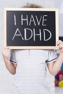 I have adhd written on chalk board being held by a child