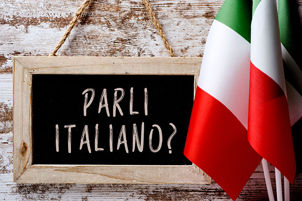 parli italiano on hanging blackboard on wall with flags