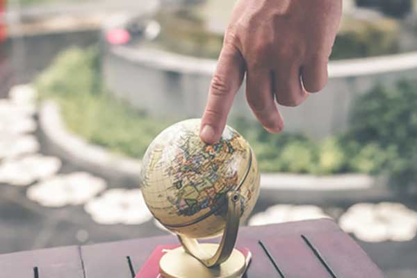 finger pointing at small globe