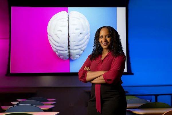 Woman standing in front of a colorful screen with an image of a brain on it.