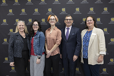 Dean Katie Kaukinen of KSU, standing with community partners in front of a black KSU backdrop