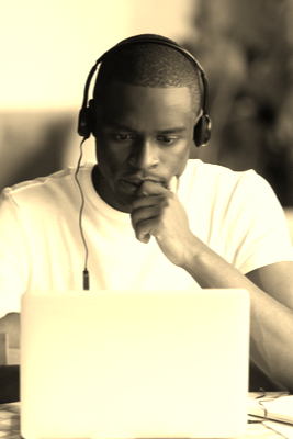 A man with headphones on, using a laptop.