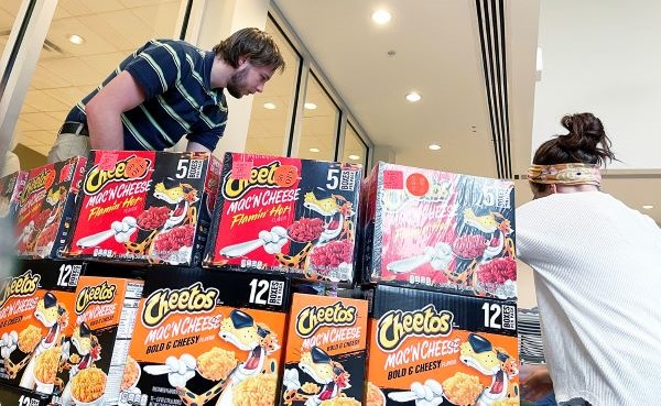 Two people stack boxes of Cheetos Mac 'N Cheese as part of a donation event.