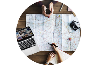 A person organizing travel plans and booking arrangements using a laptop and travel guides on a desk.