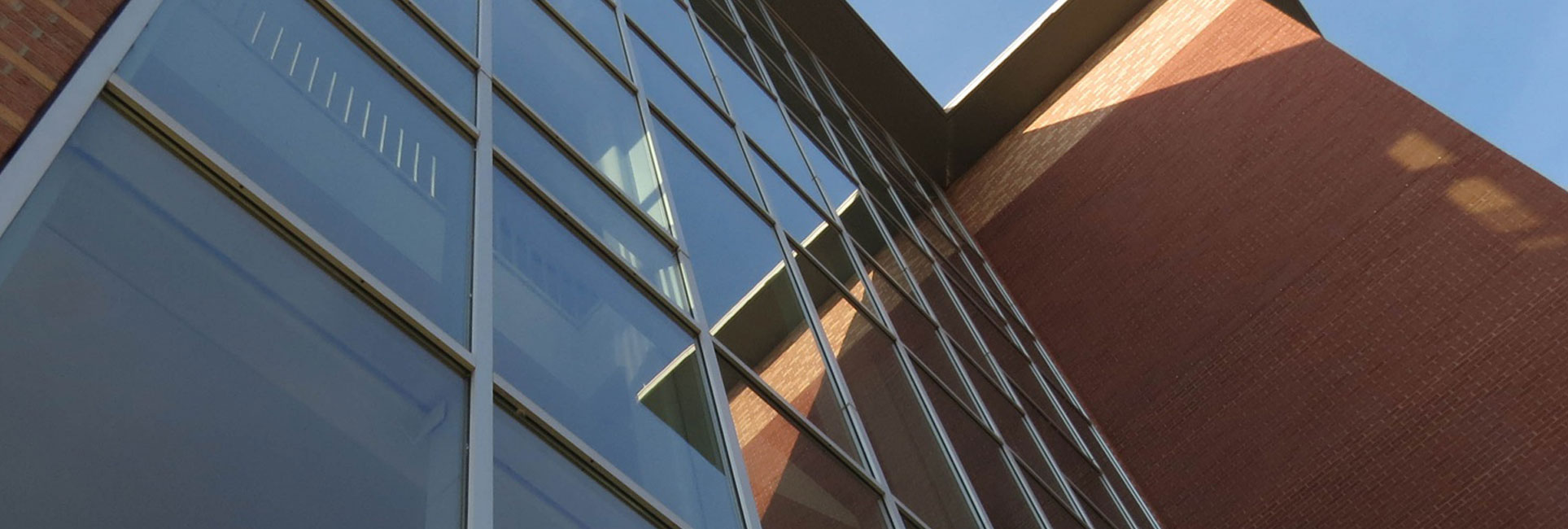 A modern architectural shot of the Kennesaw State University Norman J. Radow College of Humanities and Social Sciences building, featuring reflective glass windows and red brick walls.