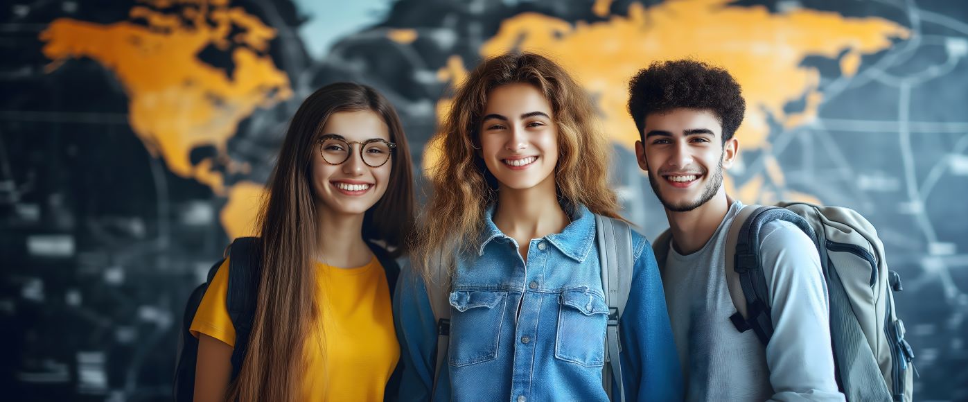 Three smiling students standing in front a large map.