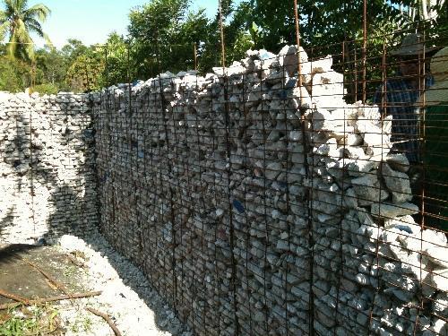 / A gabion wall under construction, filled with rocks and enclosed in wire mesh.