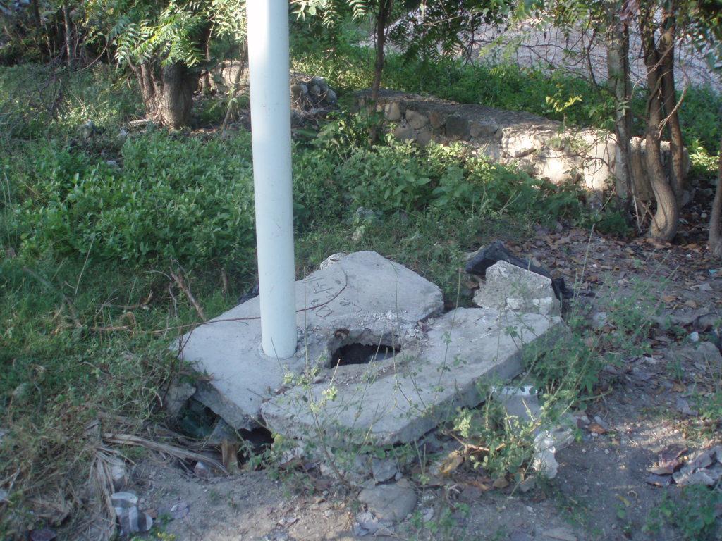  / A white pole stands on a cracked concrete base