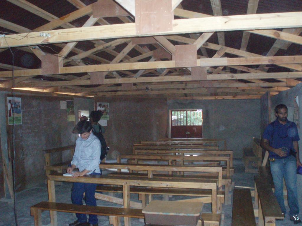 / Interior of a simple room with unfinished wooden trusses and benches.
