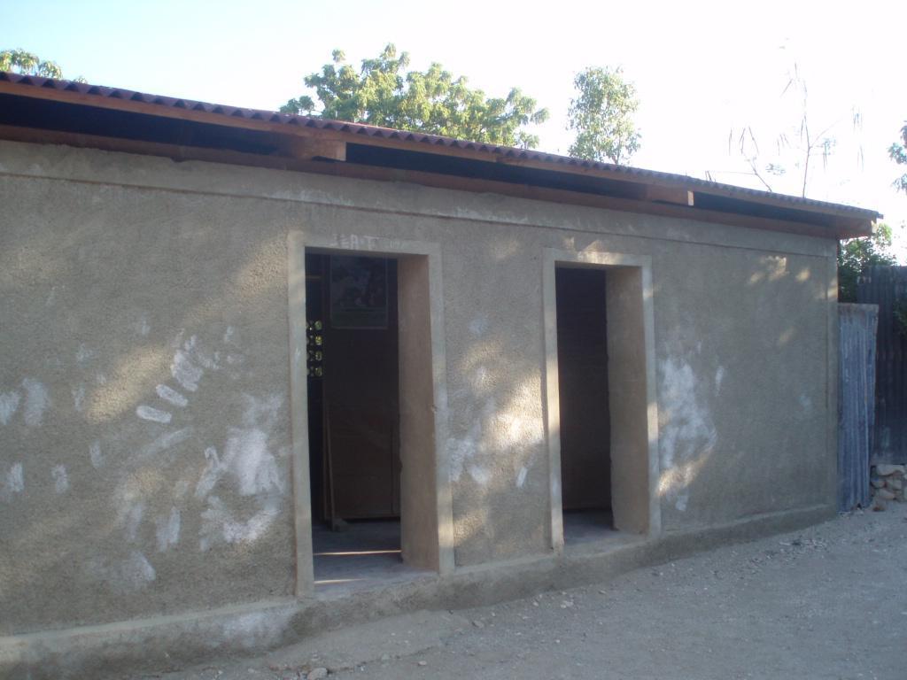  / A simple, rectangular building with two open doorways and a flat, corrugated metal roof. 