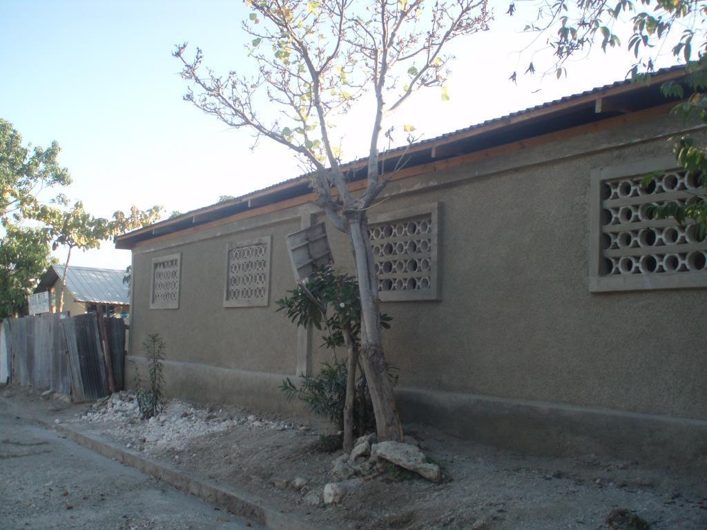  / A concrete building with decorative block windows stands beside a dirt path.
