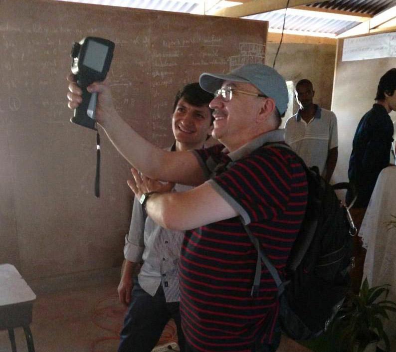  / Two people smiling and using a handheld device in a dim room with a chalkboard