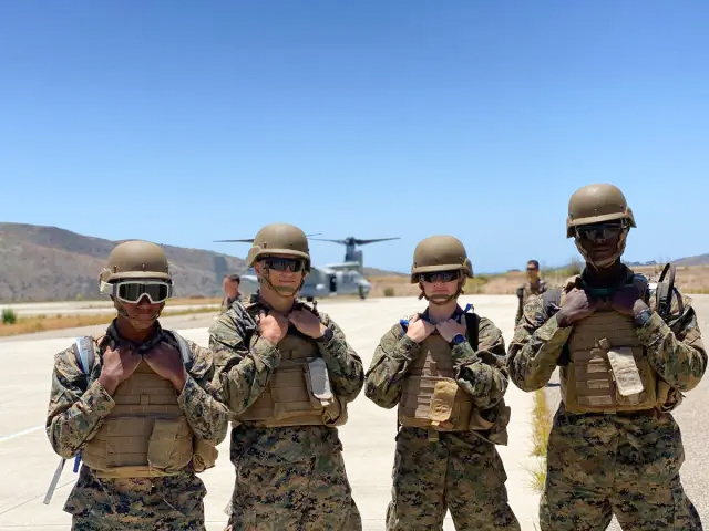 group of army professionals posing outside in front of helicopter