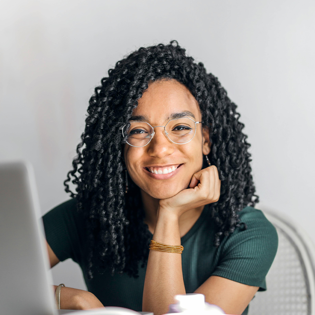 female student smiling as she sits by computer