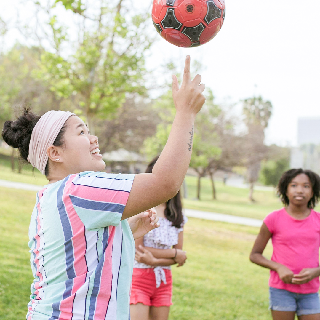 adult working with kids outside with basketball