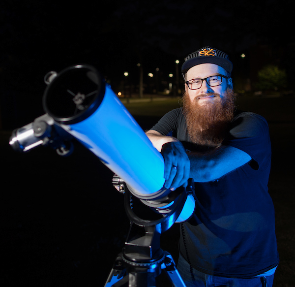 student who looks like seth rogan with telescope at night