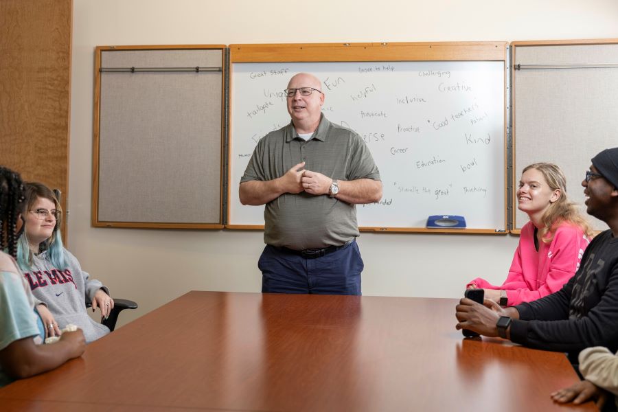 A professor lectures in front a small group