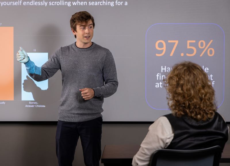 student lecturing in front of class with slideshow