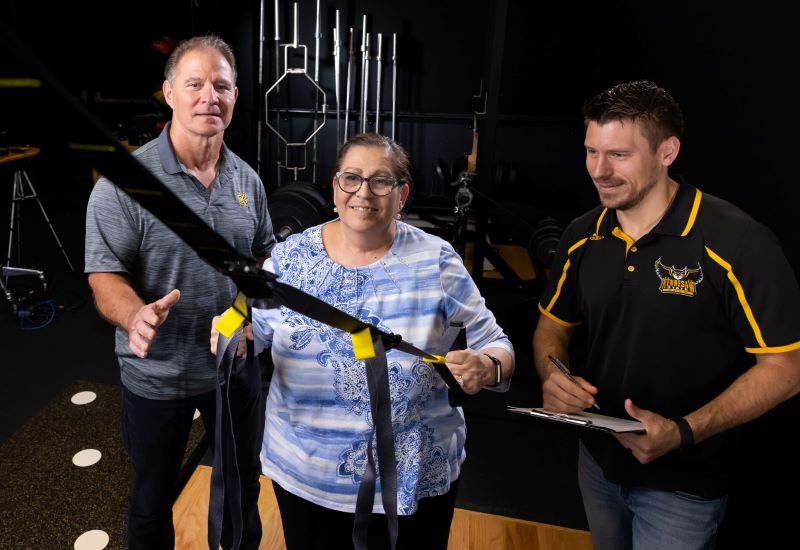 Two men and a woman stand in a gym at KSU, holding a rope.