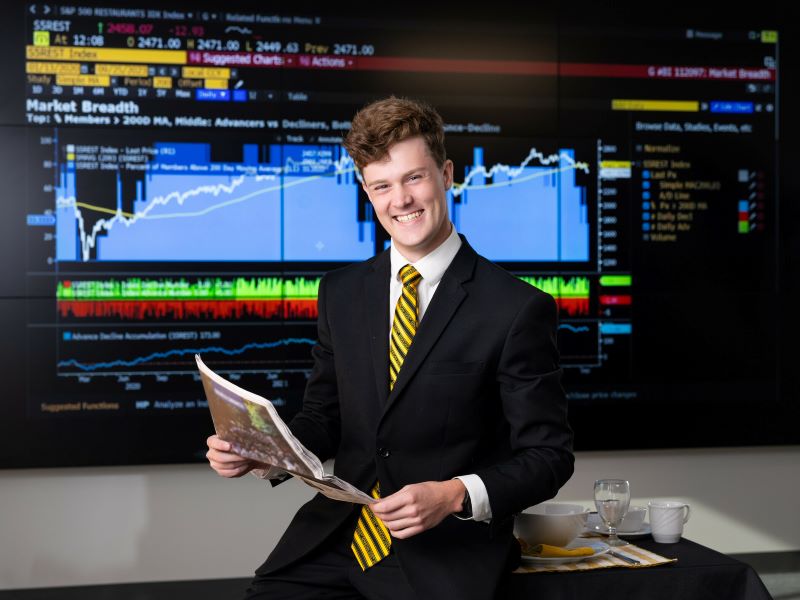 stock broker in front of huge display of stock statistics
