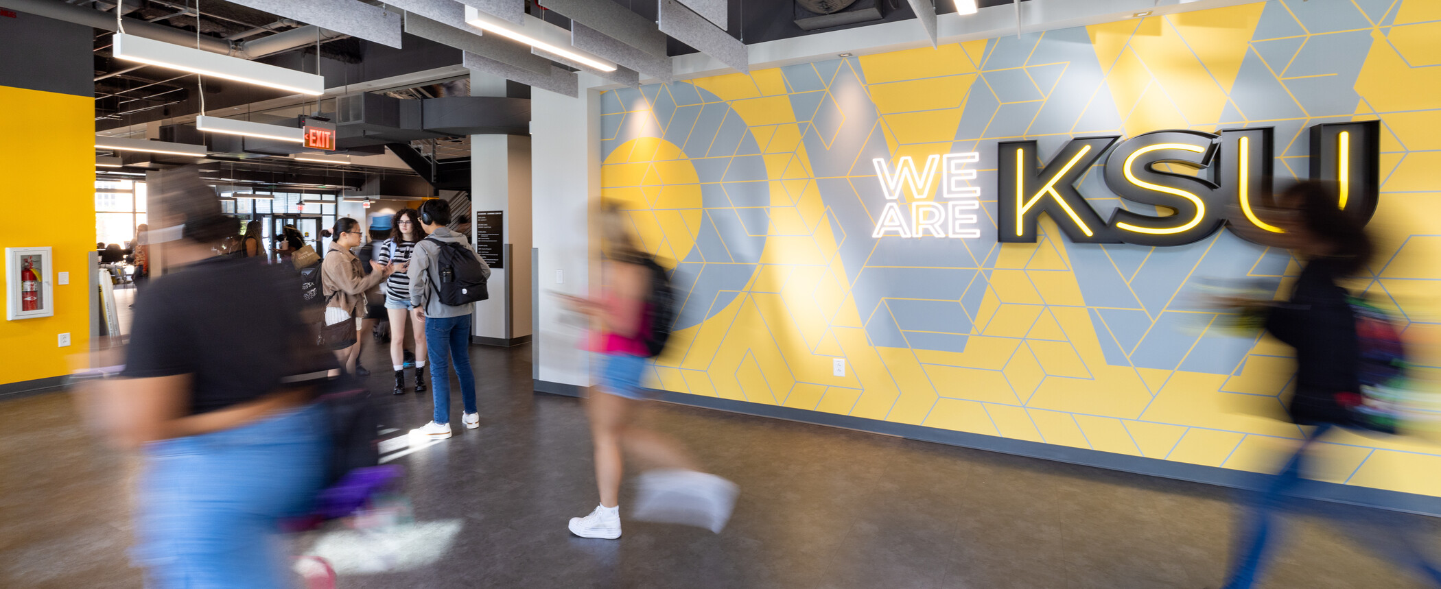 students walking in front of a "We are KSU" sign