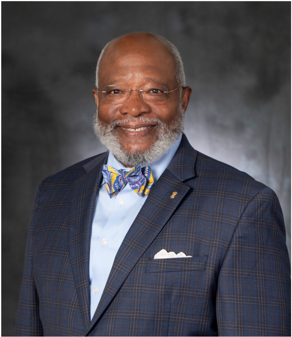 Photo of an older, smiling black male in a suit with a bow tie