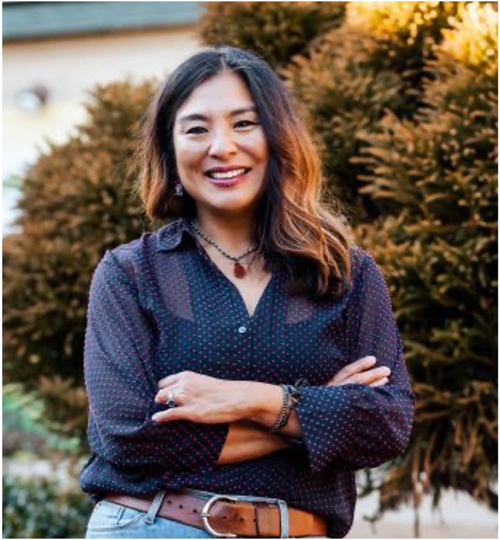 Image of a woman standing and smiling with her arms crossed