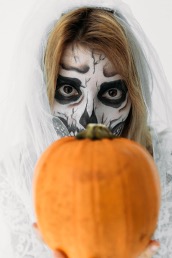Girl with painted face holding a pumpkin