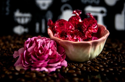 pink rose beside a bowl of candy wrapped in metallic pink foil