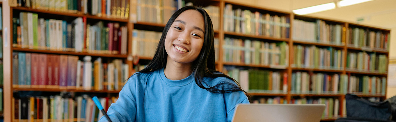 female student at desk in library smiling
