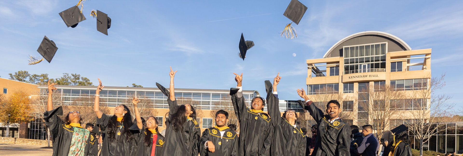 graduates throwing caps in the air on ksu campus