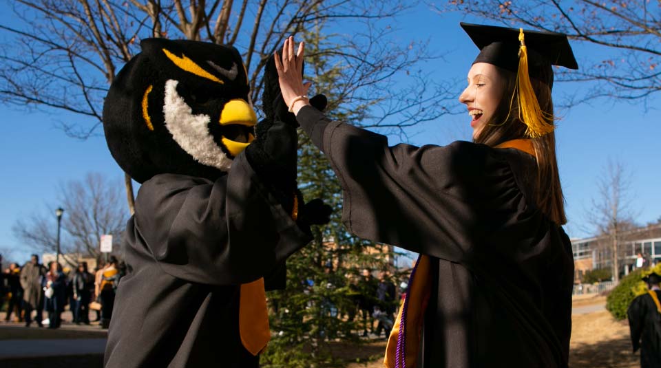 graduating student giving scrappy a high-five.