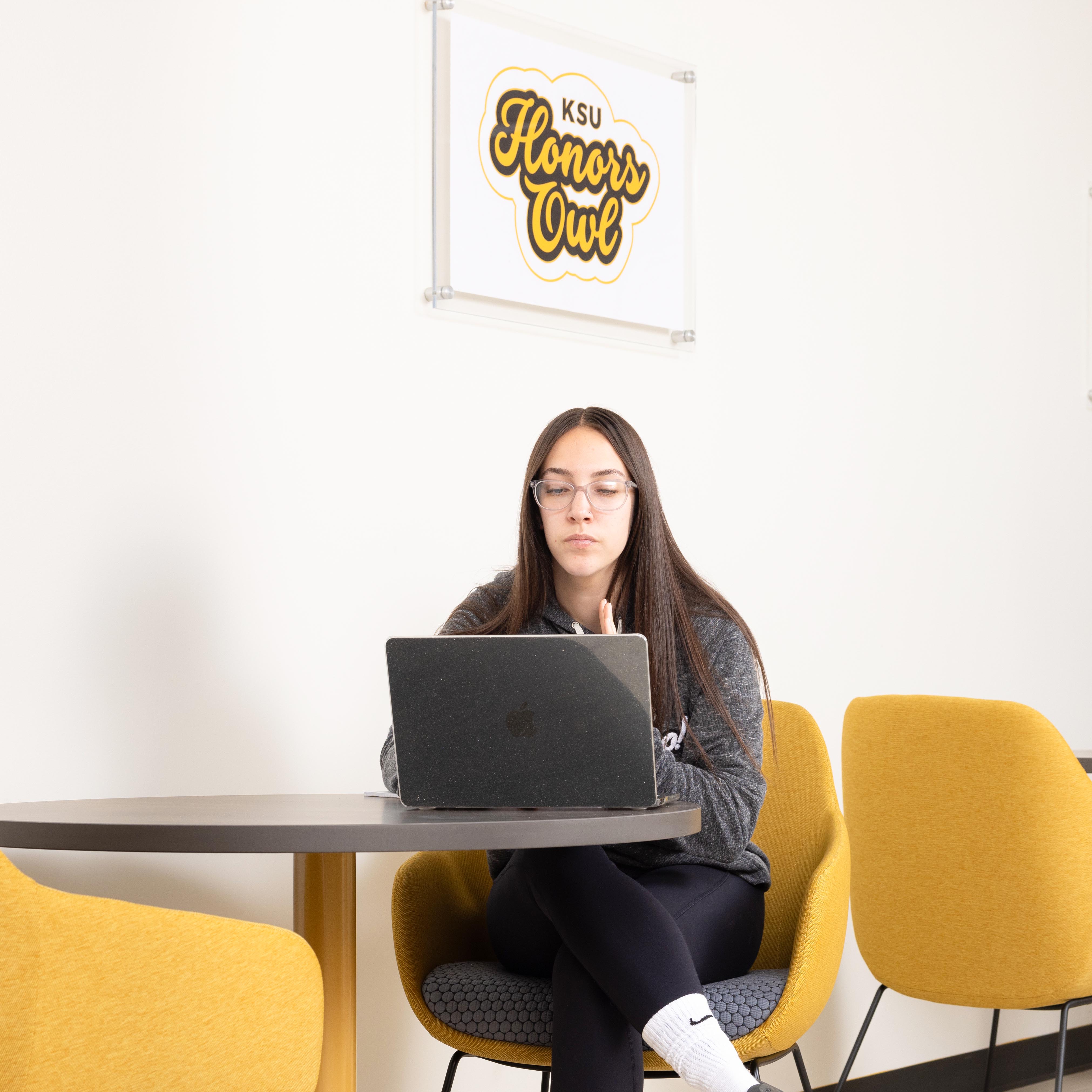 female student at ksu sitting at table with computer open