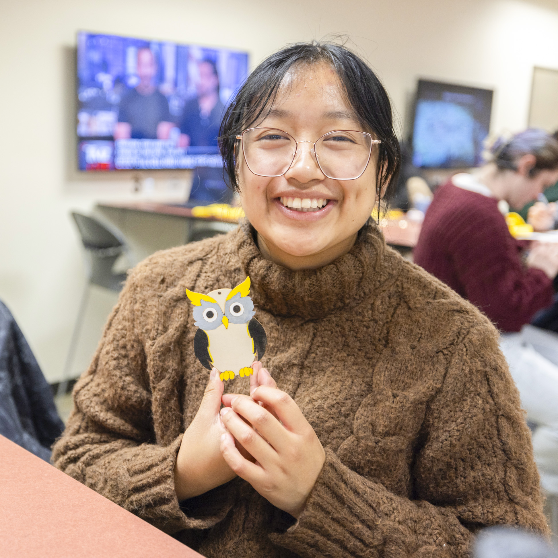 female student with glasses holding up an owl at ksu