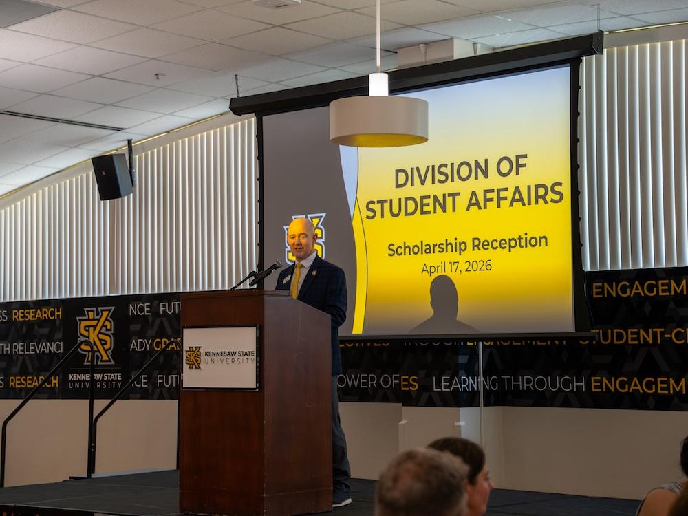  / Dr. Eric Arneson speaking at a podium.