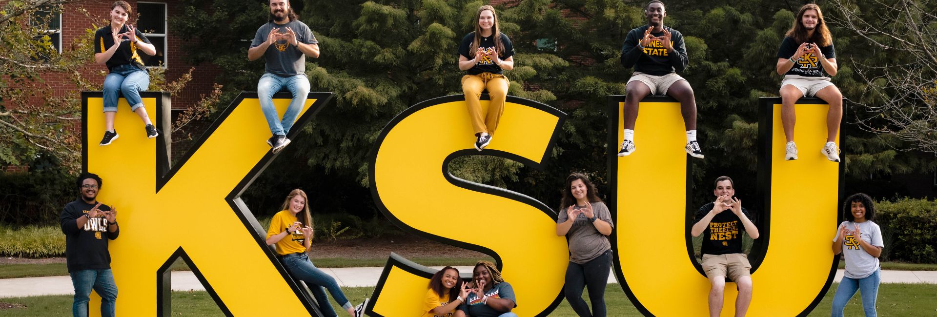 students sitting around KSU sign