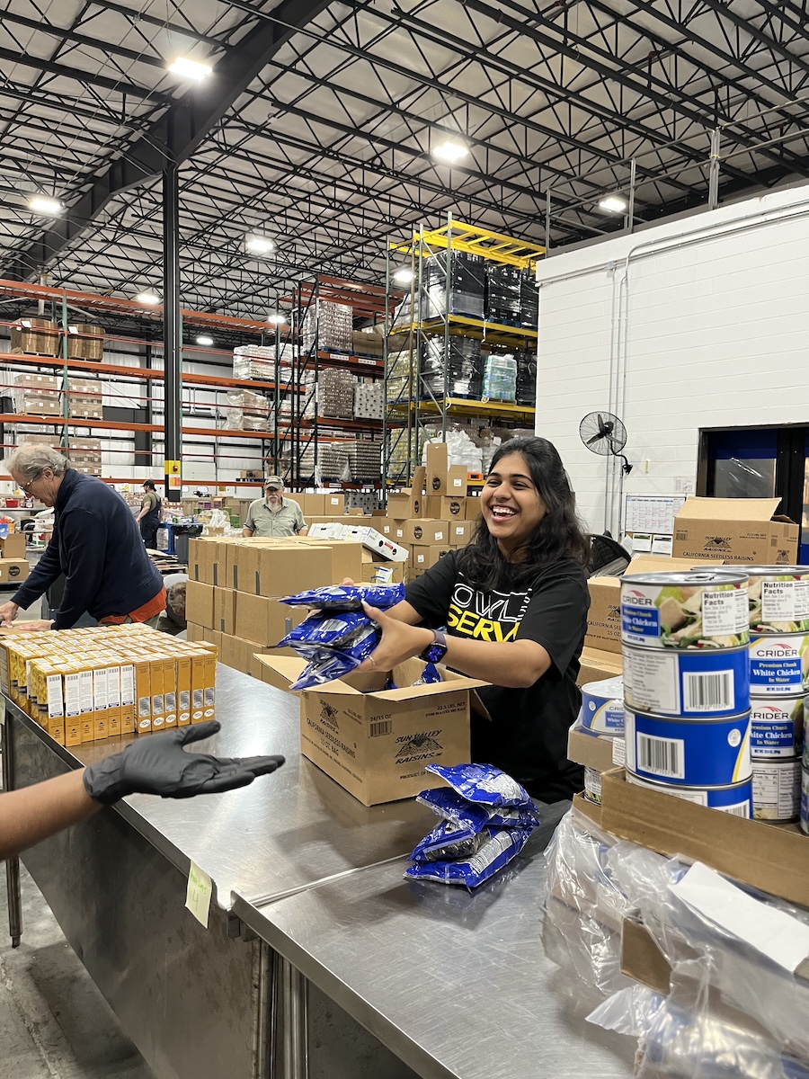 Student voulunteer hands bags of food to person