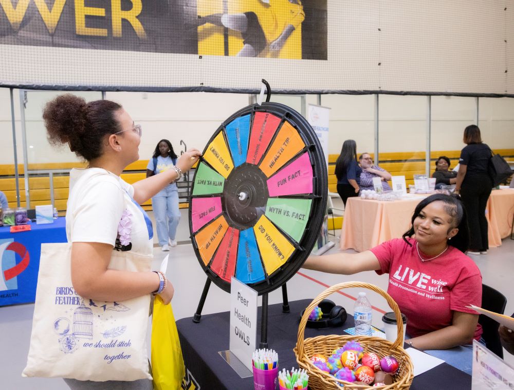 two girls spinning a prize wheel at a table