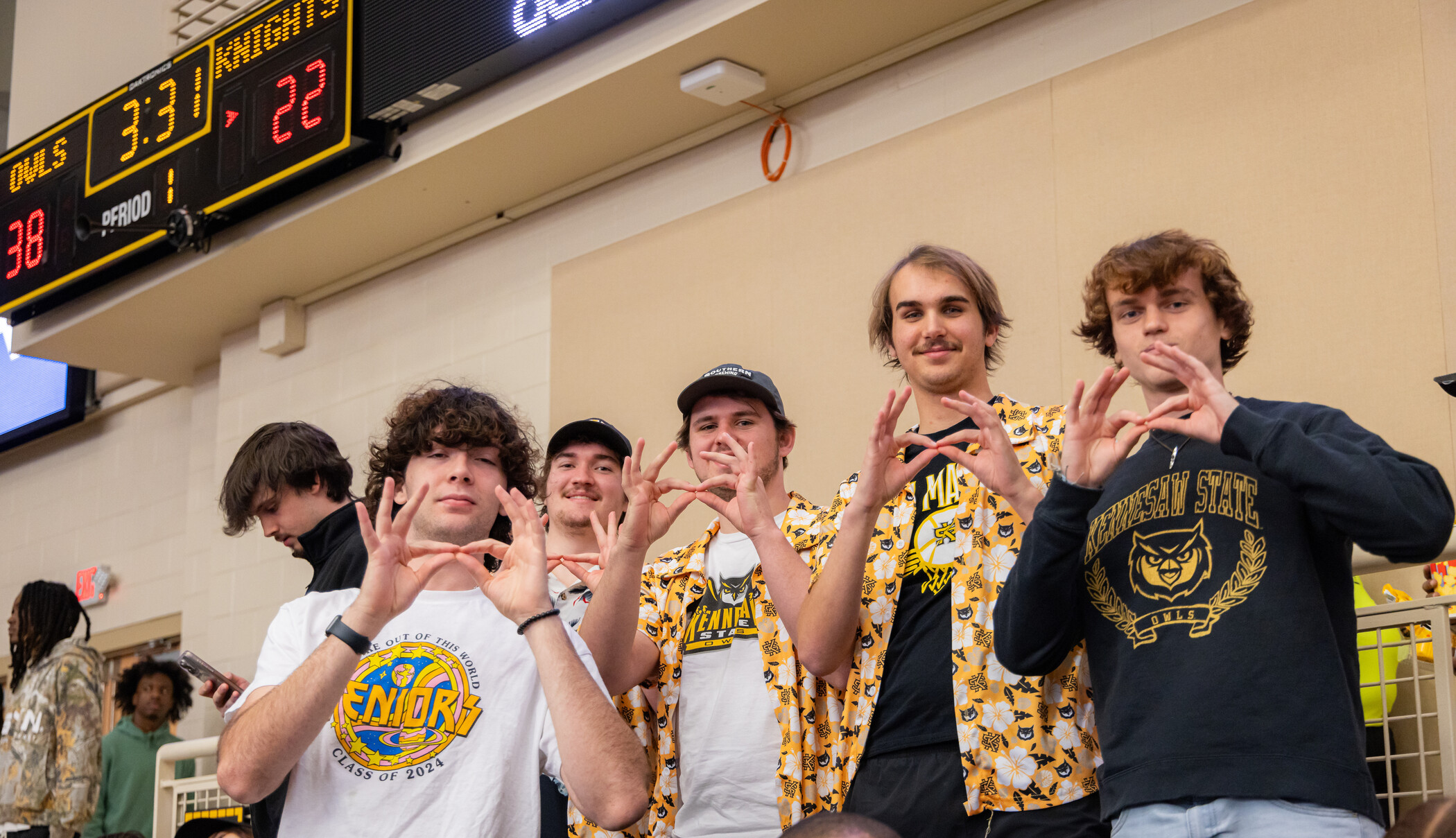 Students at a basketball game making the Go Owls gesture with their hands.