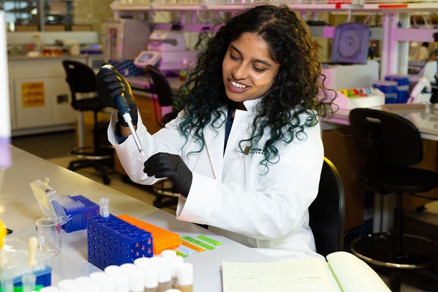 csm student in the lab holding a test tube with safety equipment on.