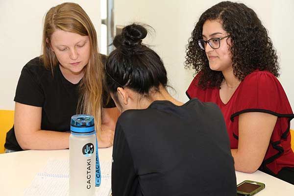 Image of three female students working on a class assignment.