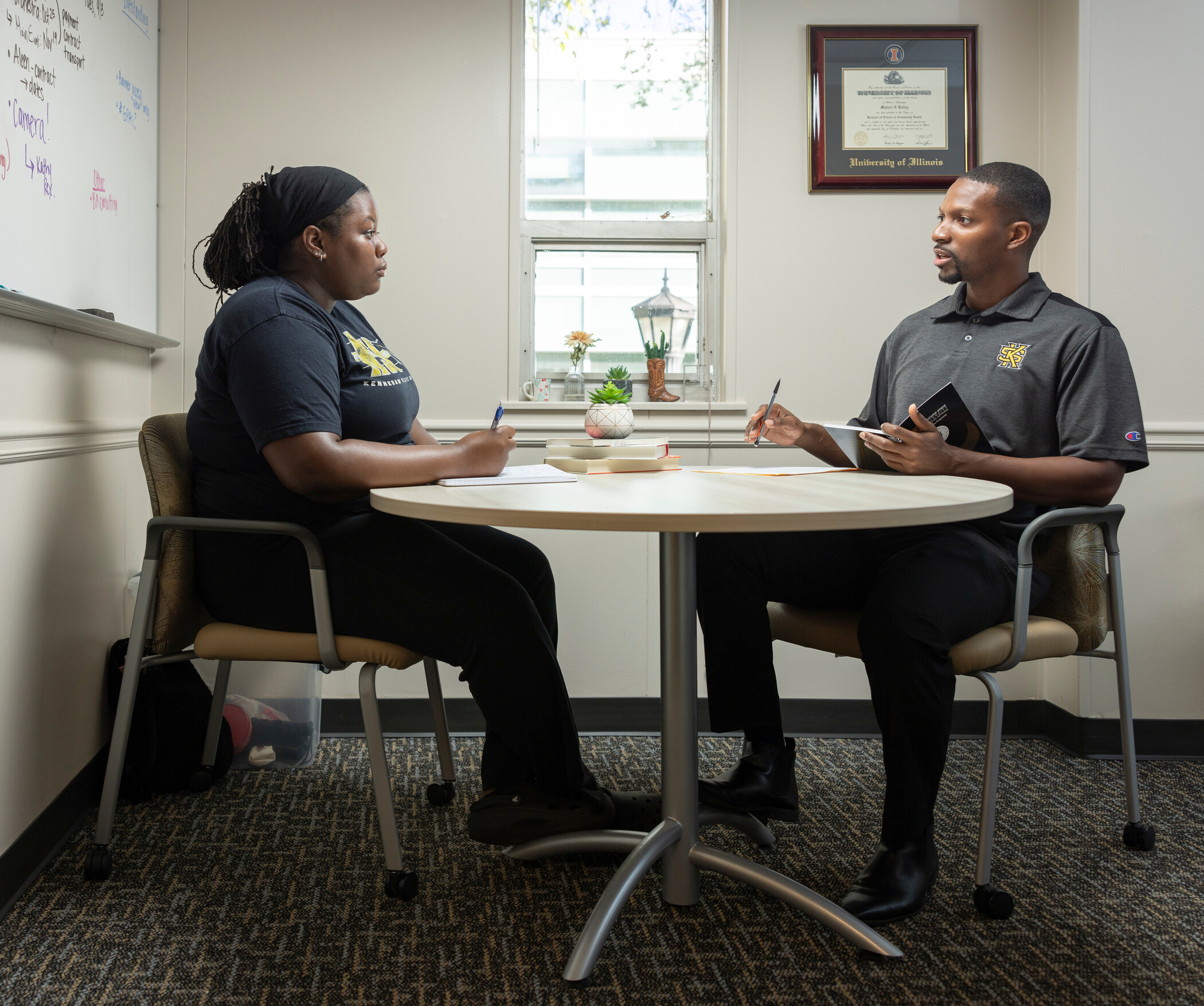 A student a coach are sitting down in a meeting together