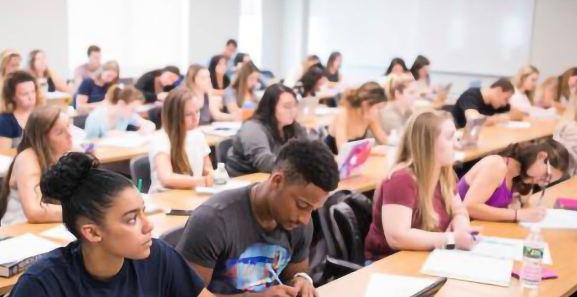 Students in a classroom sitting at desks and taking notes