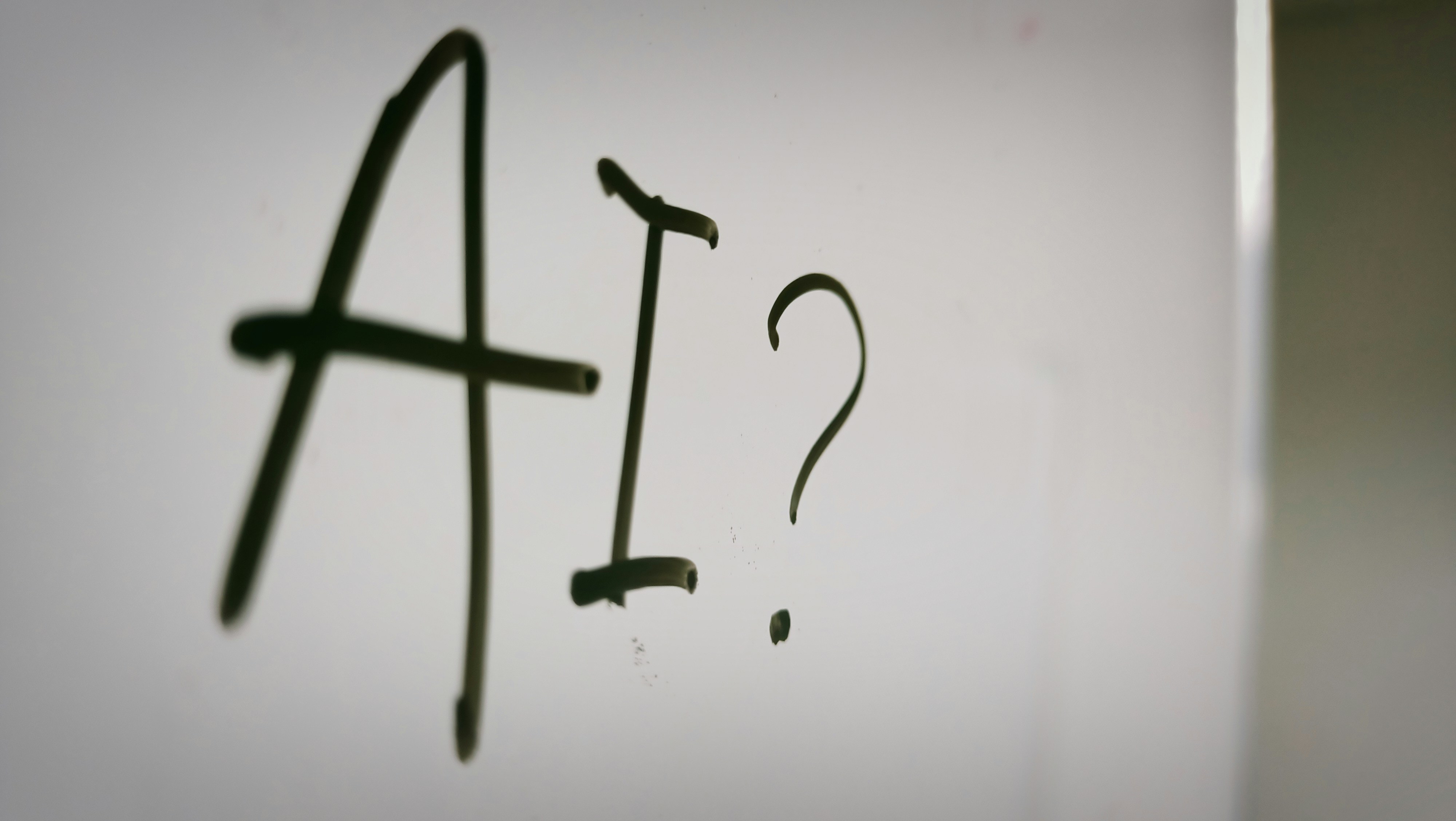 The word "AI?" written on whiteboard.