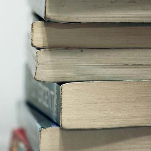 A collection of books stacked on a table, showcasing different colors and sizes.