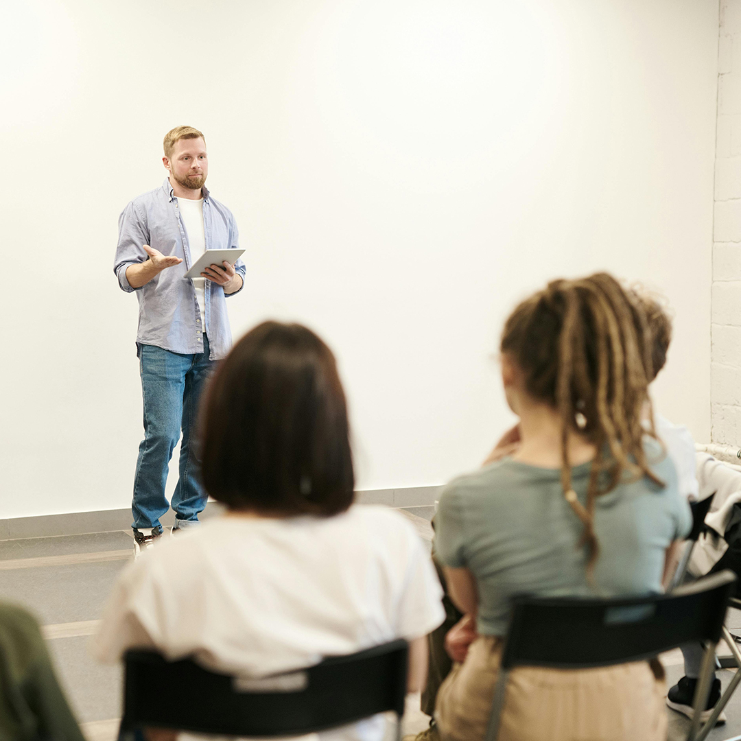 male presenter speaking infront of group of people