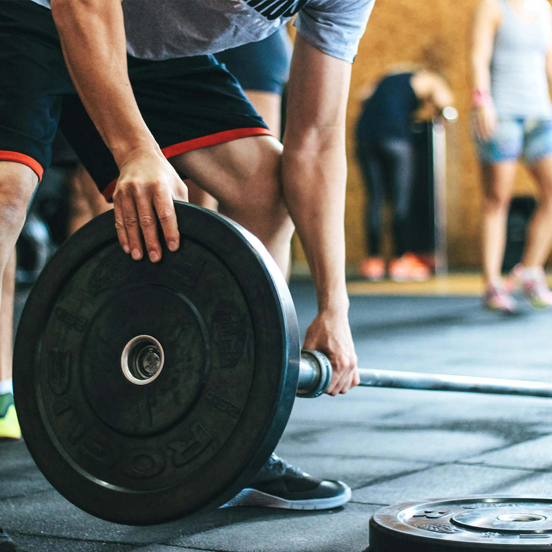 man lifting heavy weight off gym floor